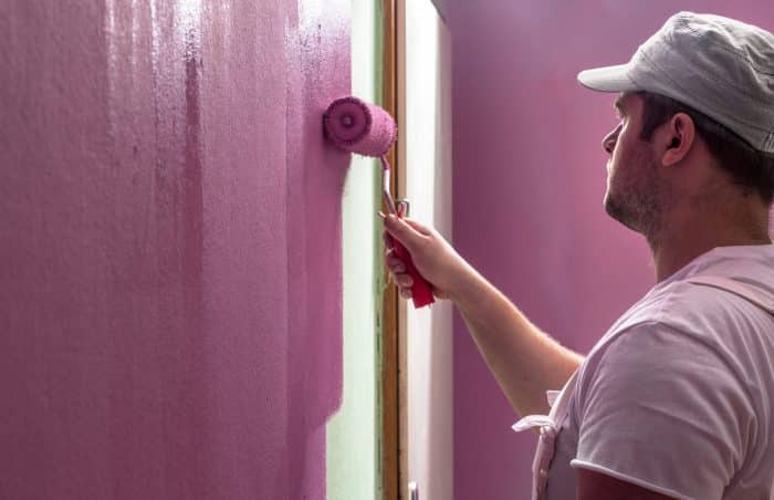 Young Man Is Painting Wall With Roller